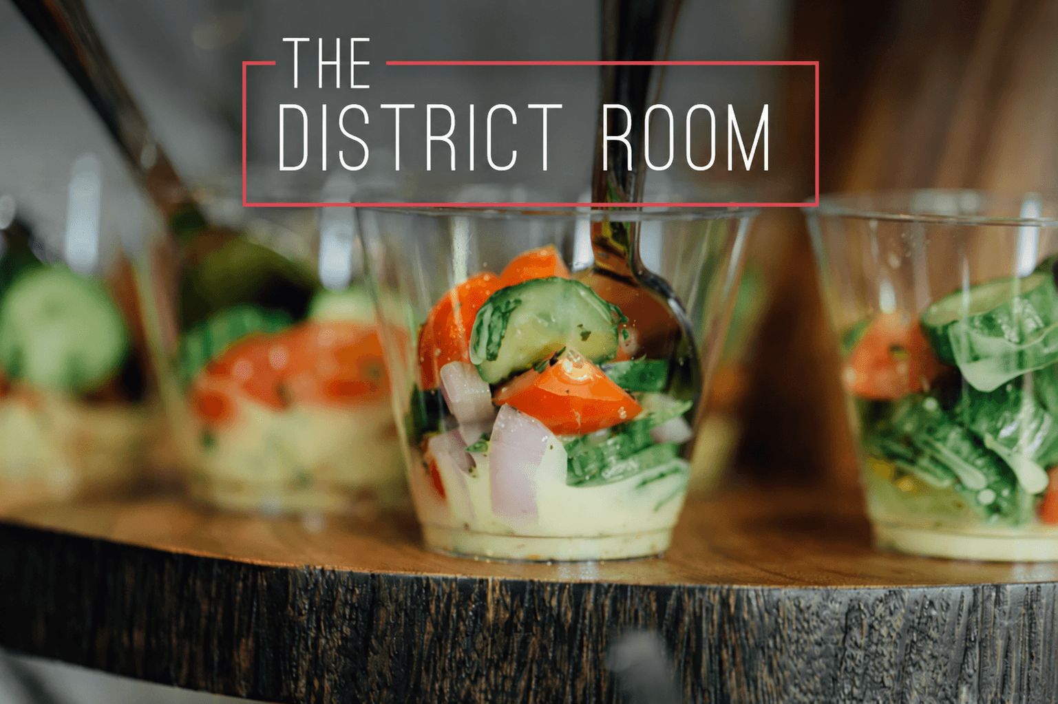 Individually plated salad cups arranged on a rustic wood serving board at a local event venue
